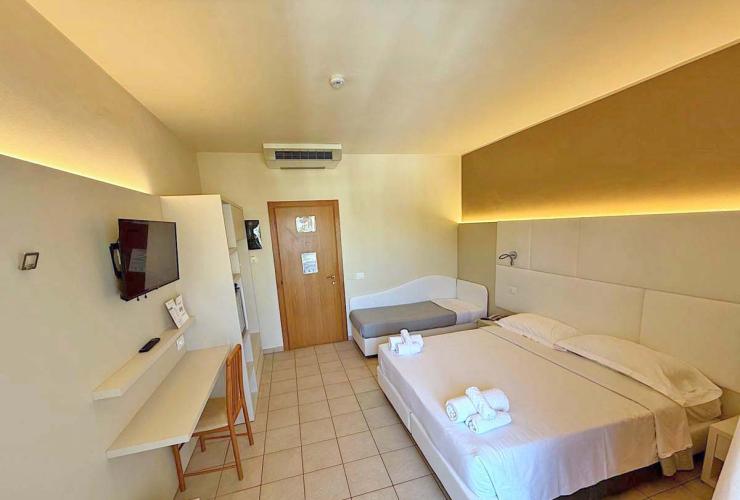 Camera moderna e accogliente, letto matrimoniale, luci soffuse, TV a parete, ambiente rilassante.